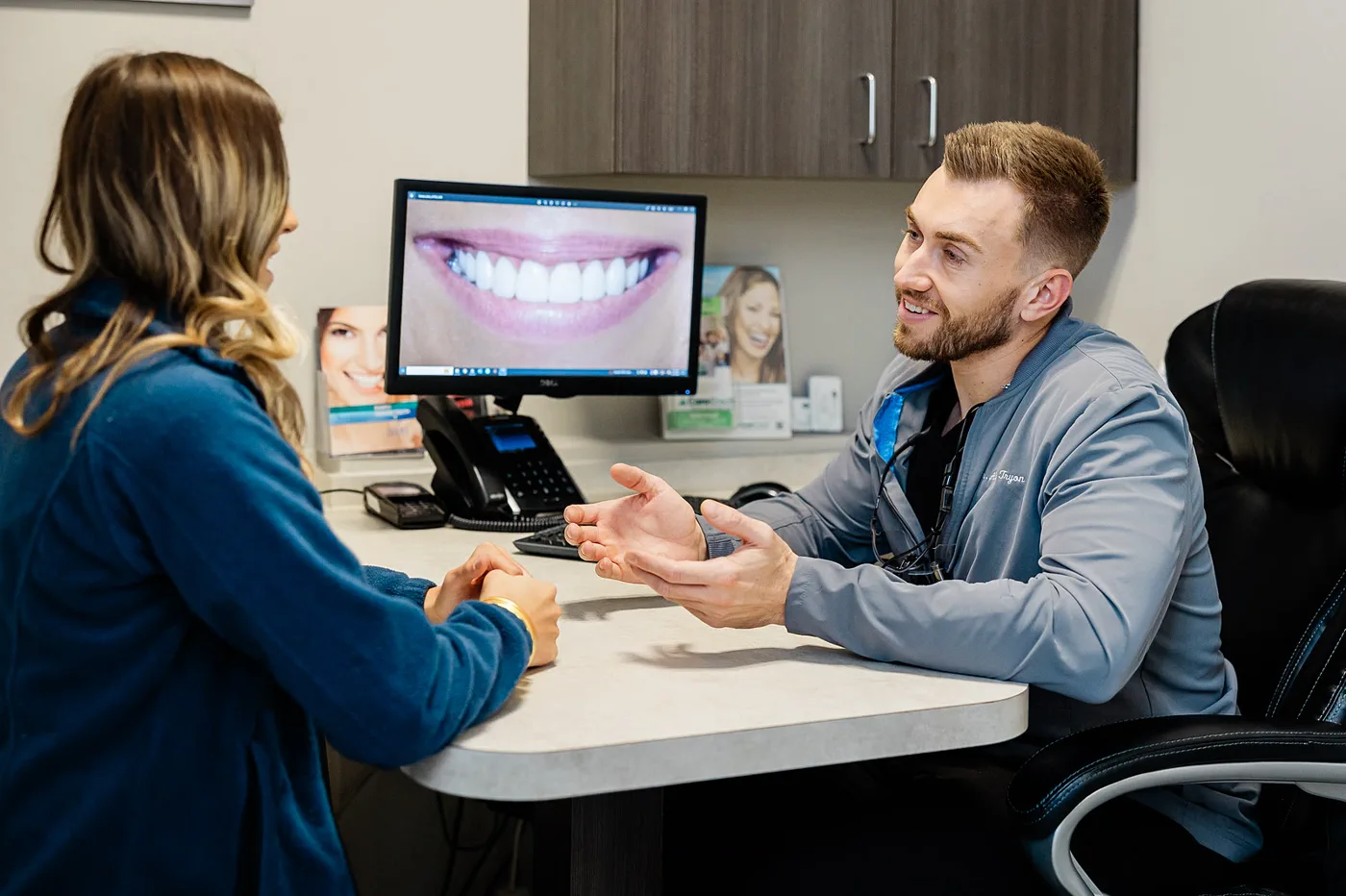 Consultation showing smile makeover possibilities on a monitor with Dr. Tryon